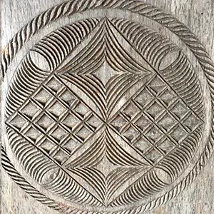 Gravure circulaire en bois représentant motifs géométriques et feuilles stylisées typiques artisanat malgache