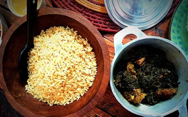 Bol en bois rempli de riz parfumé accompagné d’un plat traditionnel malgache dans un bol métallique