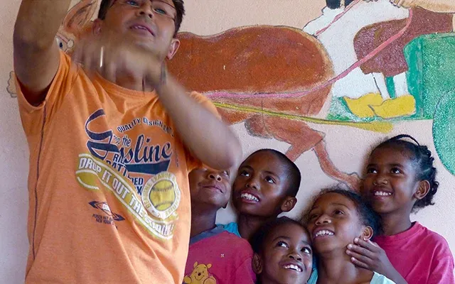 Homme faisant une animation à des enfants devant une fresque murale colorée à Madagascar