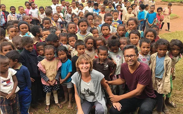 Deux voyageurs souriants entourés d’un grand groupe d’enfants à Madagascar