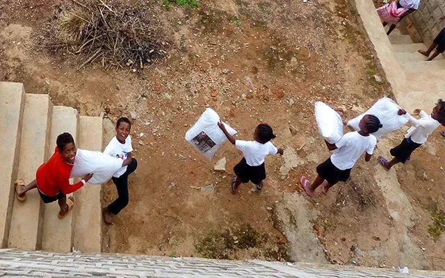 Enfants transportant des sacs en descendant des escaliers à Madagascar