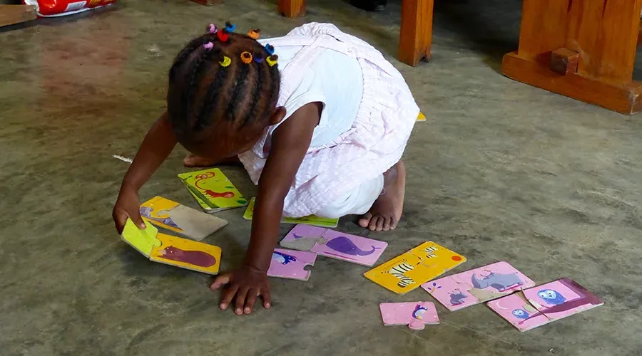 Enfant à Madagascar jouant avec des cartes illustrées colorées au sol