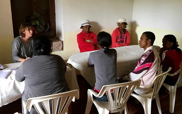 Réunion communautaire en intérieur avec participants assis autour d’une table discutant ensemble