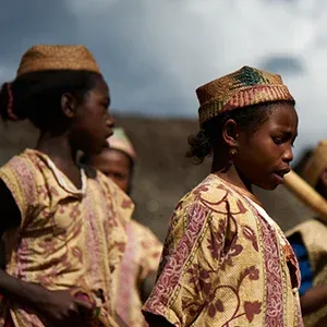 Enfants en tenues traditionnelles colorées marchant sous un ciel nuageux