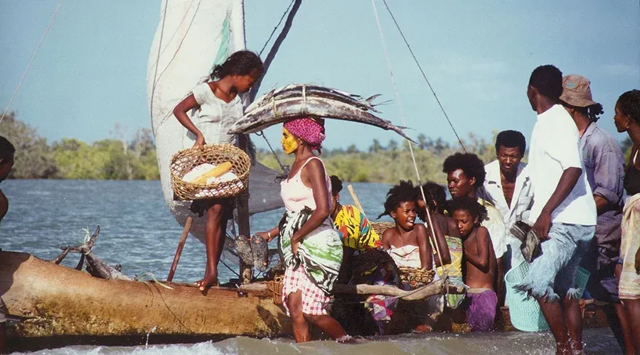 Pêcheurs madagascariens avec filets de poissons sur embarcation traditionnelle près du rivage