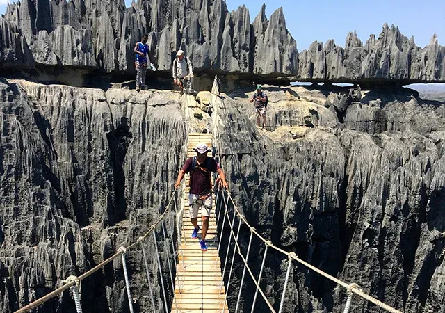 Randonneurs sur passerelle suspendue au-dessus de formations rocheuses spectaculaires de Tsingy de Madagascar