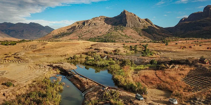 Paysage aride du sud de Madagascar avec montagnes rocheuses et rivière traversant des terres agricoles
