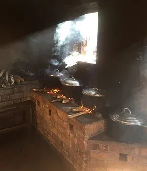 Cuisine traditionnelle malgache avec marmites en fonte sur foyer en briques et fumée