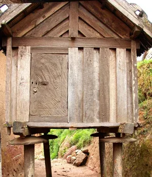 Ancienne cabane en bois sur pilotis avec porte sculptée
