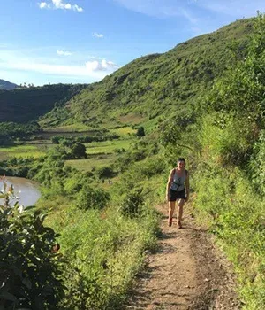 Deux randonneurs sur un sentier verdoyant bordant une rivière et des collines verdoyantes à Madagascar