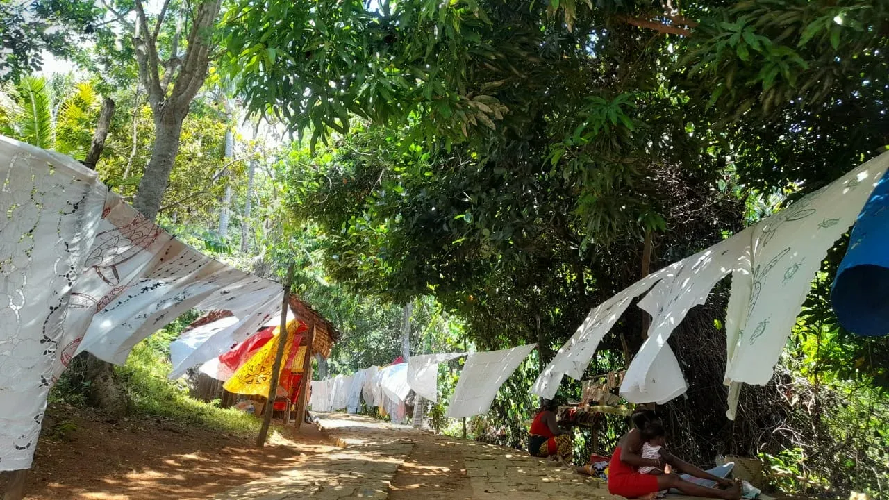 Linge séchant sous arbres dans un cadre naturel verdoyant avec enfants en arrière-plan