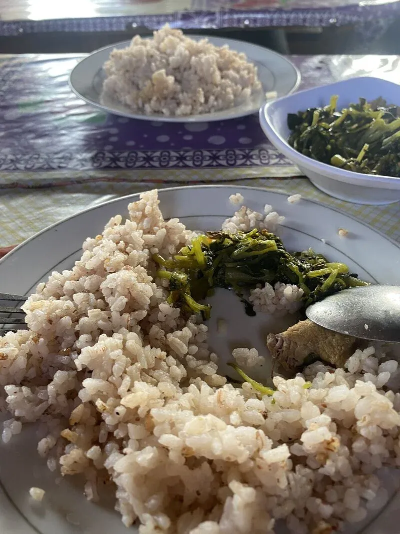 Assiette traditionnelle malgache avec riz blanc et légumes verts sautés accompagnés de viande grillée