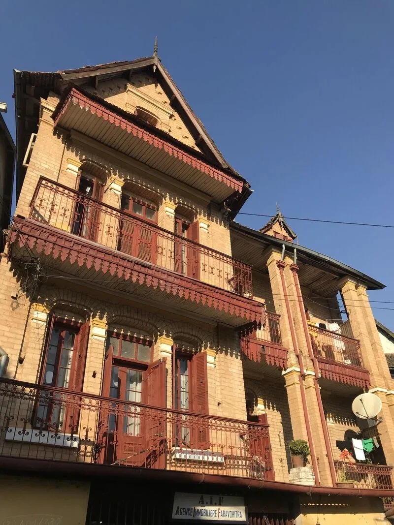 Maison coloniale malgache à balcons en fer forgé et détails architecturaux colorés sous ciel bleu