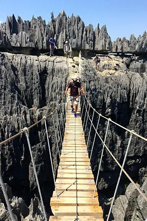Randonneurs sur passerelle suspendue au-dessus de formations rocheuses spectaculaires de Madagascar
