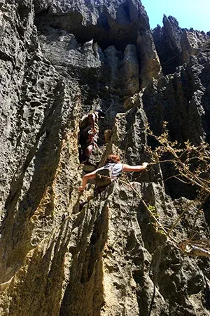 Une femme en pleine ascension sur une paroi rocheuse verticale à Madagascar