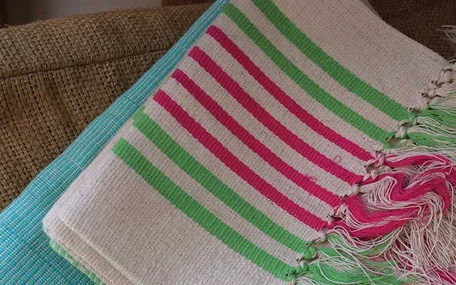 Serviettes de plage à rayures vertes et roses posées sur un fauteuil en osier