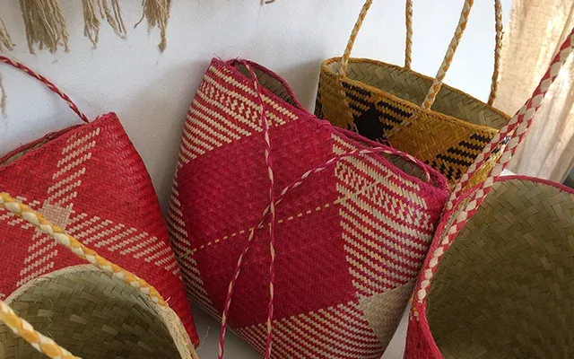 Paniers artisanaux malgaches en fibres naturelles et sacs tissés à motifs plaid rouge et crème suspendus