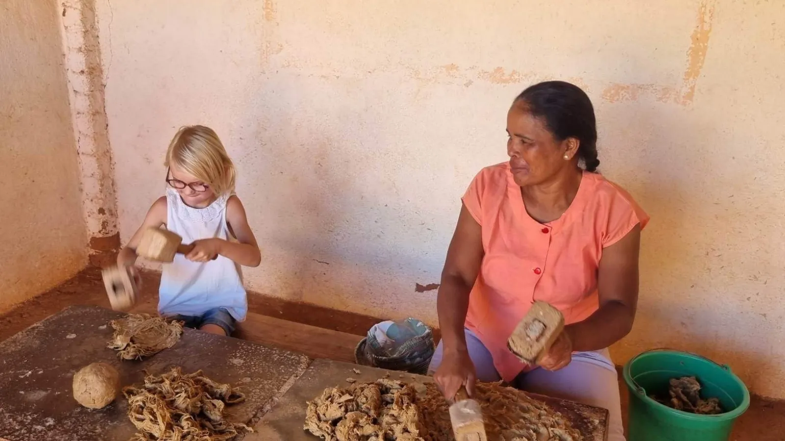 Une femme et un enfant fabriquent artisanalement des briques de terre dans un atelier traditionnel