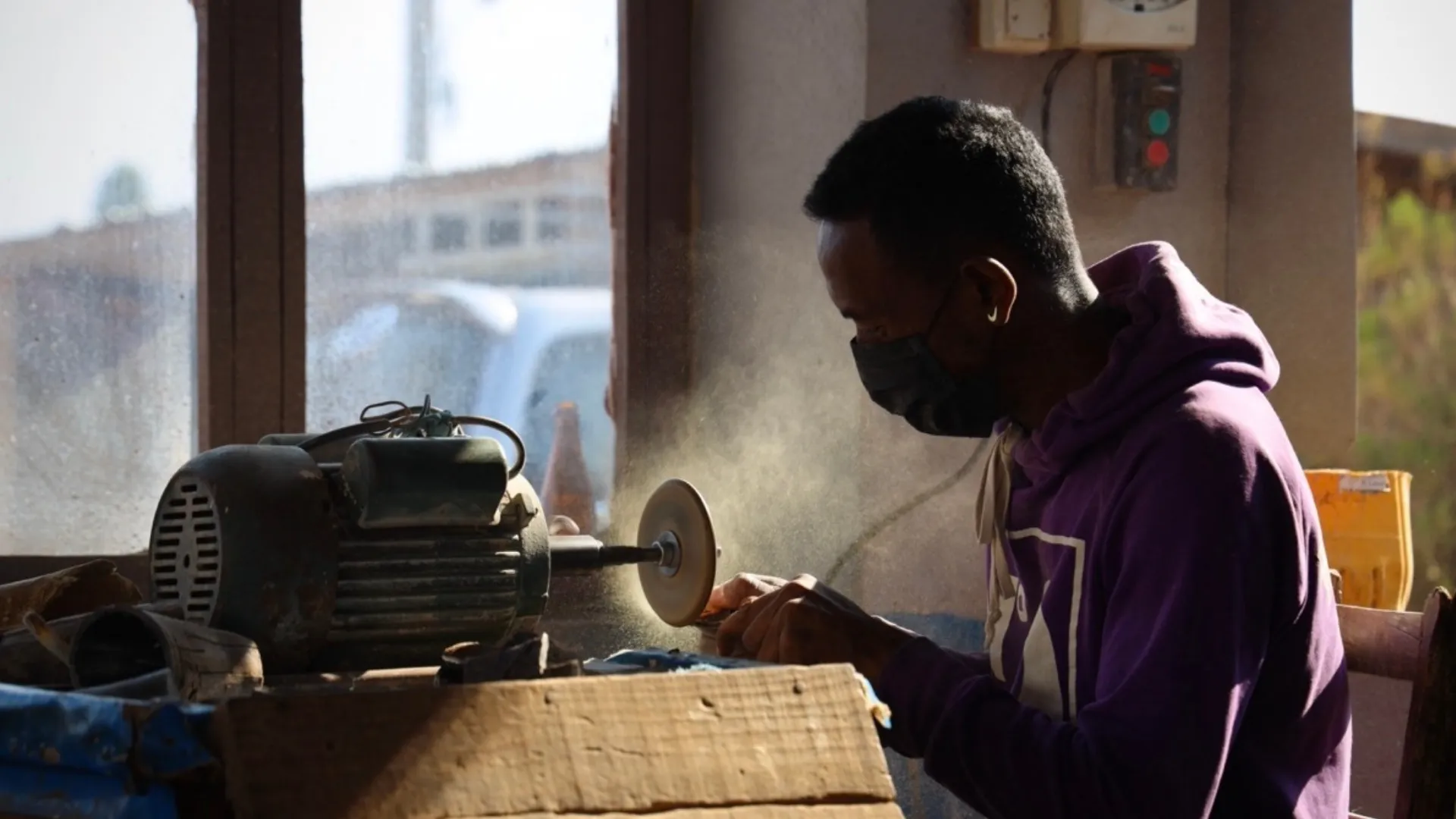 Artisan à Madagascar utilisant une meuleuse angulaire pour façonner du métal dans un atelier artisanal