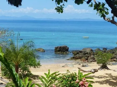 Plage paradisiaque de Madagascar avec eaux turquoise rochers et végétation luxuriante sous un ciel dégagé