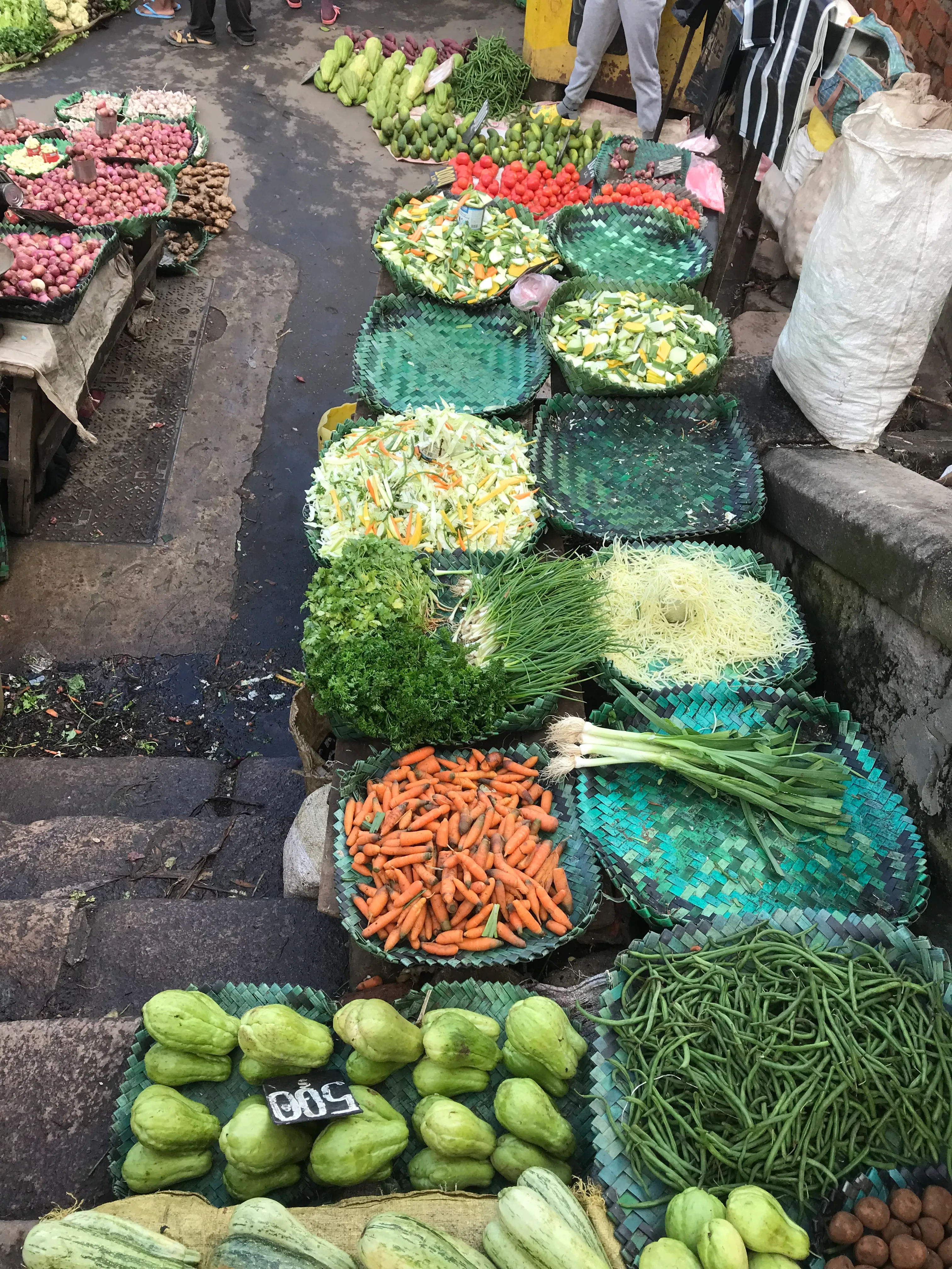 Marché malgache coloré avec légumes frais disposés en bassines et paniers sur étal
