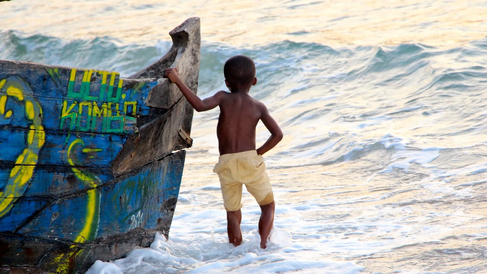 Enfant s’appuyant sur un bateau coloré