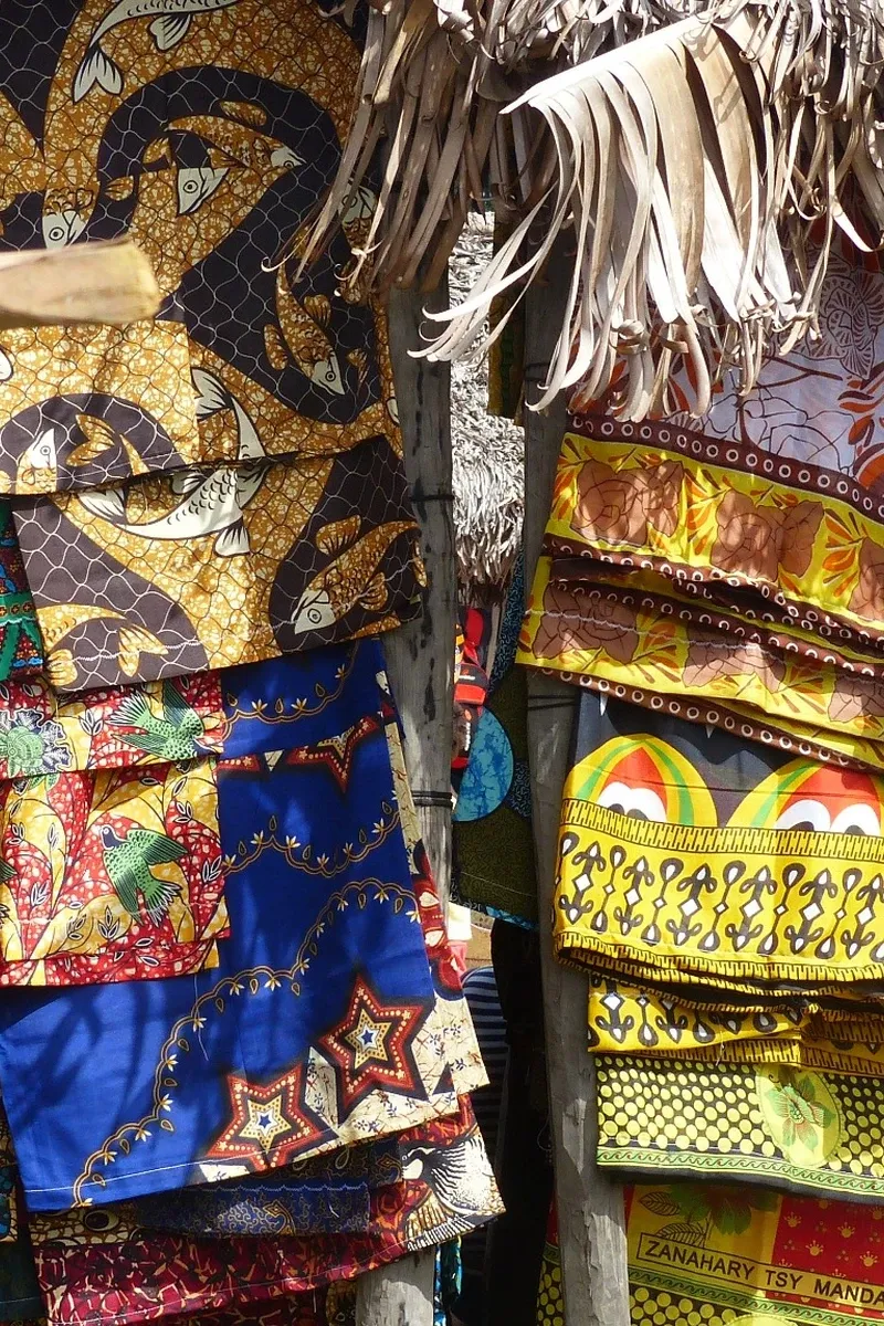 Marché malgache étalant tissus traditionnels colorés