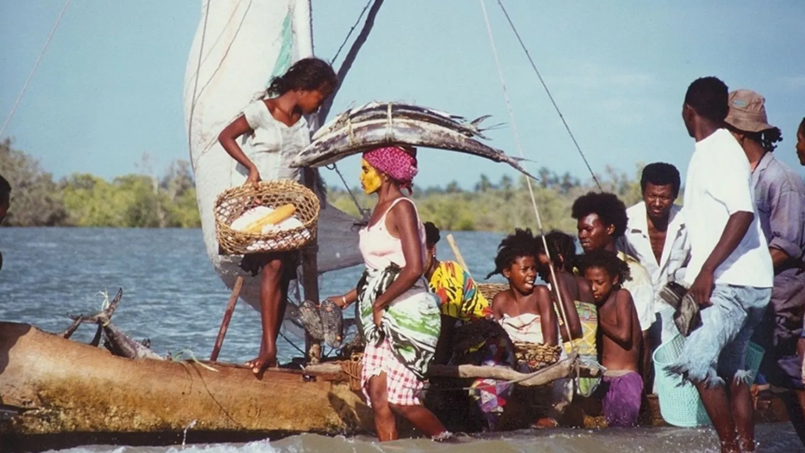 Groupe près d’un bateau traditionnel madagascar transportant des poissons et des paniers artisanaux au bord de l’eau