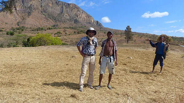 Trois hommes debout dans un paysage sec et montagneux sous un ciel dégagé.
