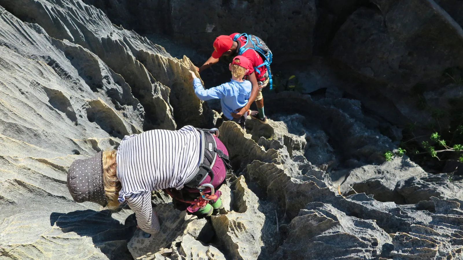Deux enfants équipés en randonnée escaladent un sentier rocheux escarpé à Madagascar