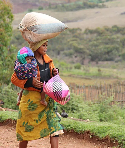 Une jeune femme et son enfant portant un sac sur la tête.